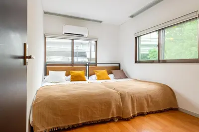 a bedroom with a large bed with yellow pillows at \u4e0a\u5317\u6ca2\u6238\u5efa\u3066 in Tokyo