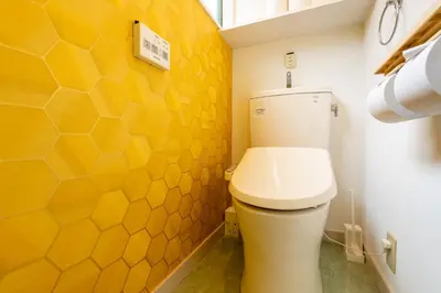 a bathroom with a toilet and a yellow wall at \u4e0a\u5317\u6ca2\u6238\u5efa\u3066 in Tokyo