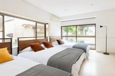 a row of four beds in a room with windows at \u4e0a\u5317\u6ca2\u6238\u5efa\u3066 in Tokyo