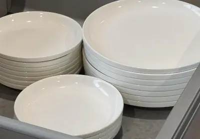 three stacks of white plates sitting on a shelf at \u4e0a\u5317\u6ca2\u6238\u5efa\u3066 in Tokyo