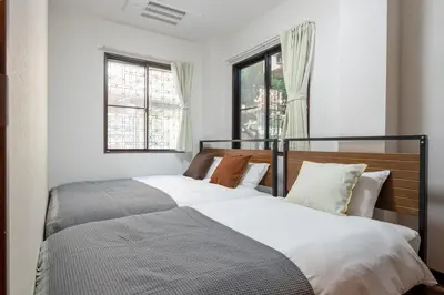 two beds in a bedroom with two windows at -Numabukuro House- 10-minute walk from Numabukuro station in Tokyo
