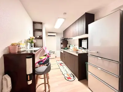 a small kitchen with a refrigerator and a stool at ManOku in Tokyo