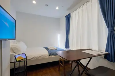 a bedroom with a bed and a table and a tv at LIFE TOWN Yotsugi in Tokyo