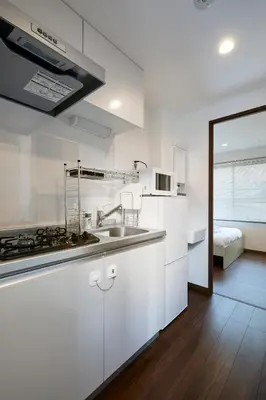 a kitchen with white cabinets and a sink and a bed at LIFE TOWN Yotsugi in Tokyo