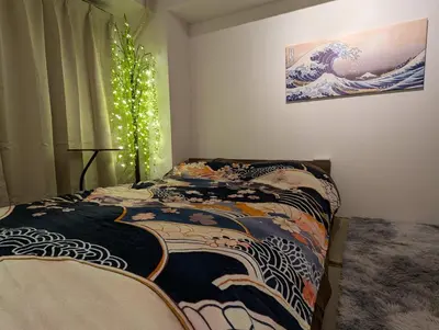 a bedroom with a bed with a painting on the wall at Asakusa Tokyo T'sRoom in Tokyo