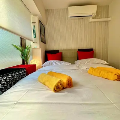 two towels are laying on a white bed at PLAZA SINJUKU Cozy Mansion #2 in Tokyo