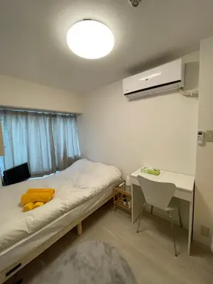 a small room with a bed and a desk and a lamp at PLAZA SINJUKU Cozy Mansion #2 in Tokyo