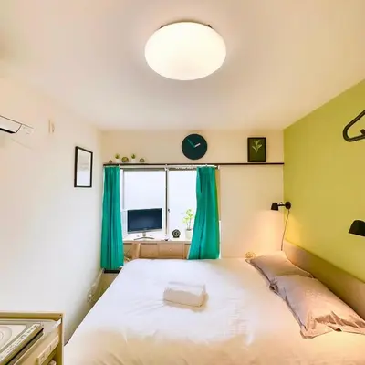 a bedroom with a bed with green walls and a window at PLAZA SINJUKU Cozy Mansion #2 in Tokyo