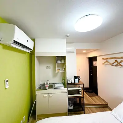a small kitchen in a small room with green walls at PLAZA SINJUKU Cozy Mansion #2 in Tokyo