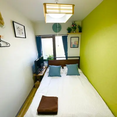 a bed in a room with a green wall at PLAZA SINJUKU Cozy Mansion #2 in Tokyo