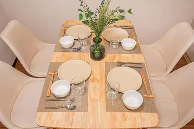 a wooden table with plates and glasses and a vase with flowers at \u65b0\u5bbf\u6b4c\u821e\u4f0e\u753a\u5f92\u6b65\u4e09\u5206\u9418\u4e09\u623f\u4e00\u5ef3\u8fd1\u9130\u4f0a\u52e2\u4e39 in Tokyo