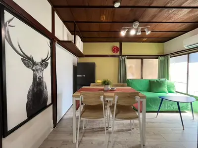 a dining room with a table and a green couch at NakakasaiKodateNKK1 in Tokyo