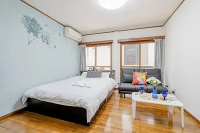 a bedroom with a bed and a couch and a table at \u30a2\u30f3\u30c9\u30b9\u30c6\u30a4\u4e2d\u91ce5\u4e01\u76ee102 in Tokyo