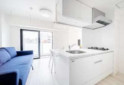 a white kitchen with a sink and a blue couch at Ikebukuro Base in Tokyo