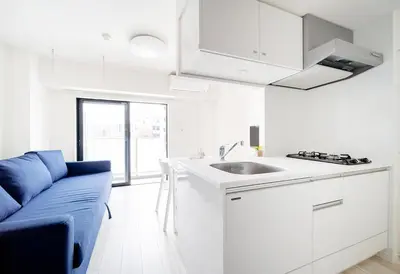a white kitchen with a blue couch and a sink at Ikebukuro Base in Tokyo