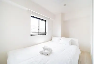 a white bed in a white room with a window at Ikebukuro Base in Tokyo