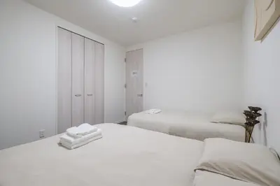two beds in a white room with white walls at UN-Villa in Tokyo