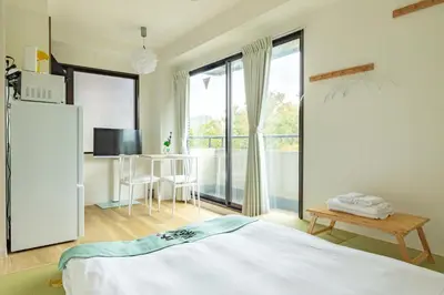 a bedroom with a bed and a table and a large window at Shinjuku Waseda Haruno B&B in Tokyo