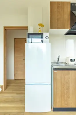 a white refrigerator in a kitchen with wooden cabinets at Shinjuku Waseda Haruno B&B in Tokyo