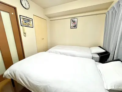 two beds in a hotel room with a clock on the wall at S,F, Heights - Vacation STAY 18008 in Tokyo