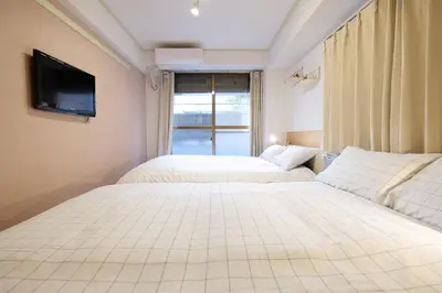 two beds in a bedroom with a tv on the wall at Heisei Mansion - Vacation STAY 18017 in Tokyo