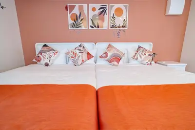a bed with an orange blanket and pillows on it at Higashi-Shinjuku 901 in Tokyo
