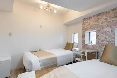 a room with two beds and a table and chairs at \u6771\u65b0\u5bbf 1110 in Tokyo