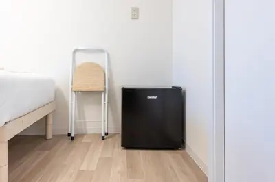a black refrigerator in a room next to a bed at \u6771\u65b0\u5bbf 1101 in Tokyo