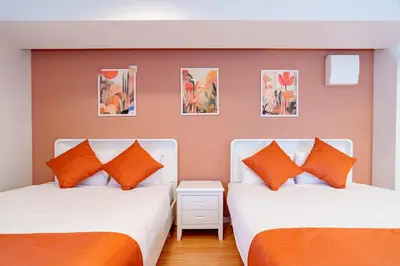 two beds in a room with orange pillows at Higashi-Shinjuku 902 in Tokyo
