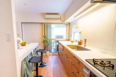 a kitchen with a sink and a counter with stools at Higashi-Shinjuku 902 in Tokyo