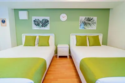 two beds in a room with green walls at Higashi-Shinjuku 905 in Tokyo