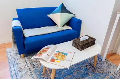 a blue couch and a table with a book on it at Higashi-Shinjuku 905 in Tokyo