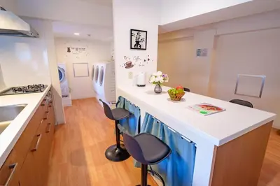 a kitchen with a white counter and stools in it at Higashi-Shinjuku 903 in Tokyo
