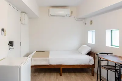 a small bedroom with a bed and a table at \u6771\u65b0\u5bbf 1105 in Tokyo