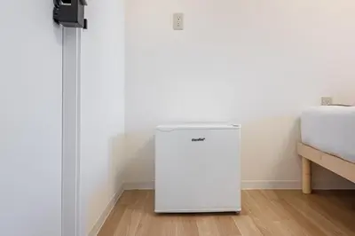 a white refrigerator in a room next to a bed at \u6771\u65b0\u5bbf 1108 in Tokyo