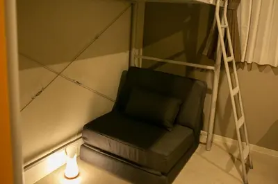 a chair in a room with a ladder and a lamp at \u85cd-Ai-ASAKUSA in Tokyo