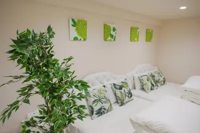 a white couch with pillows and a plant in a room at SLEEPLAB THE STAY Casual \u65b0\u5bbf2 in Tokyo