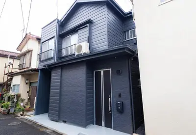 a black house with a door and a balcony at K's Casa西新井 駅徒歩4分 ディズニー車26分 56m2 ハンギングチェア 下町の快い暮らし in Tokyo