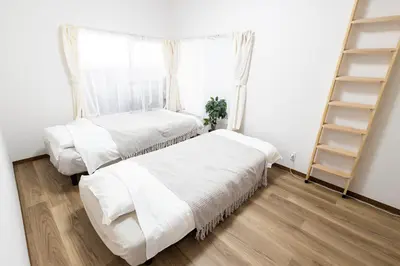 two beds in a room with a window at K's Casa西新井 駅徒歩4分 ディズニー車26分 56m2 ハンギングチェア 下町の快い暮らし in Tokyo