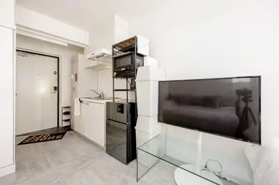 a living room with a large flat screen tv on a wall at \u30a2\u30f3\u30c9\u30b9\u30c6\u30a4\u767d\u91d16\u4e01\u76ee301 in Tokyo