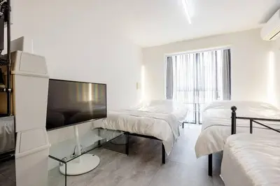 a white room with two beds and a flat screen tv at \u30a2\u30f3\u30c9\u30b9\u30c6\u30a4\u767d\u91d16\u4e01\u76ee301 in Tokyo
