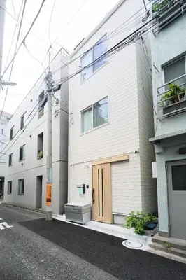 a white building with a brown door on a street at URBAN HOUSE HATAGAYA - Vacation STAY 52809v in Tokyo
