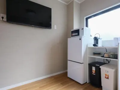 a kitchen with a white refrigerator and a tv on the wall at HOTEL Kyo in Tokyo