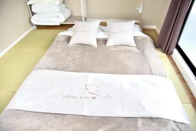 a bed with white sheets and pillows in a room at HOTEL Kyo in Tokyo