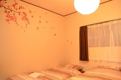 a bedroom with two beds and a window with a tree mural at Shibuya South JP House in Tokyo
