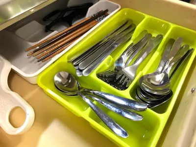 a green plastic tray with spoons and forks and knives at Shibuya South JP House in Tokyo