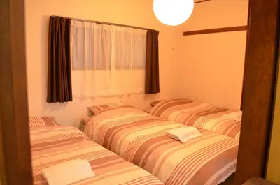 three striped beds in a room with a window at Shibuya South JP House in Tokyo