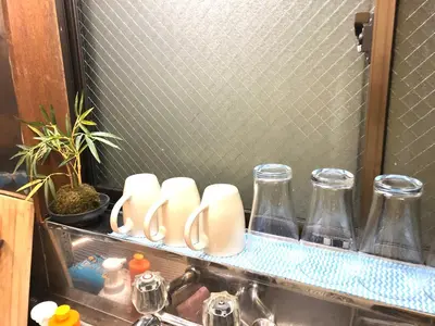 a kitchen sink with a shelf with glass bottles and a sink at Shibuya South JP House in Tokyo