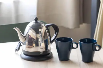 a tea kettle sitting next to two cups on a table at Harebare apartment for max 4ppl 3mins walk from Kiba station 3F in Tokyo