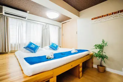 a bedroom with a large bed with blue pillows at \u685c\u306e\u5ddd16 \u6c60\u888b\u4e00\u6238\u5efa \u6c60\u888b\u99c5 5\u5206 2-11\u4eba\u4e28Ikebukuro Villa Ikebukuro 5 minutes 2-11 people in Tokyo